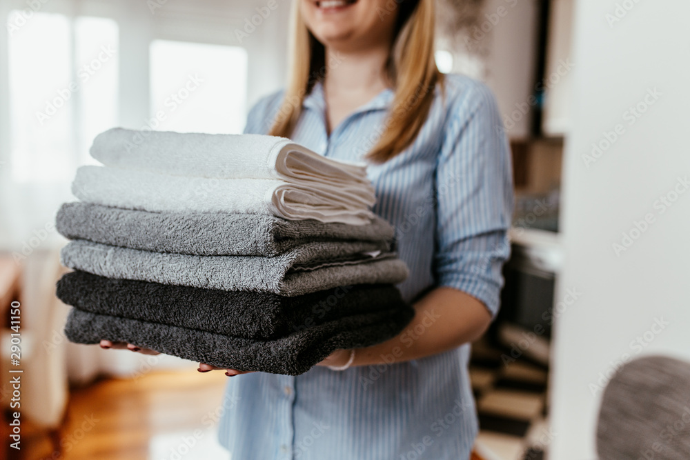 Young woman holding a pile of ironed clean towels. Stock Photo | Adobe ...
