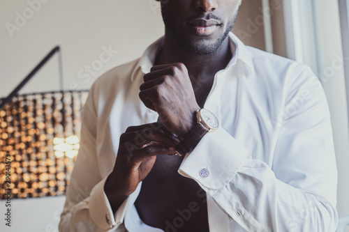 Fotografía Sexy confident male in opened white shirt is putting on his wrist watch