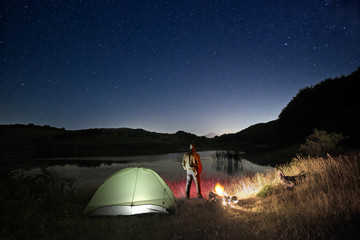 Wall Mural - Man And Wild Camp By The Lake Under Starry Sky