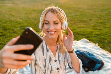 Poster - Beautiful young blonde girl relaxing on a lawn at the park