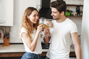 Wall Mural - Image of caucasian young couple drinking wine together in apartment