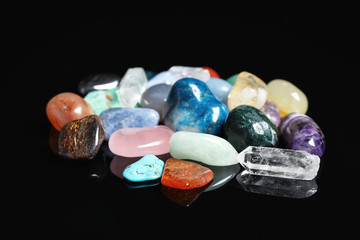 Pile of different beautiful gemstones on black background