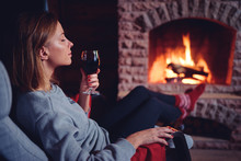 Cozy Home. Close Up Of Young Woman Drinking Red Wine Near The Fireplace.