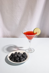 Wall Mural - Plate of blue berries with cocktail beverage above white desk