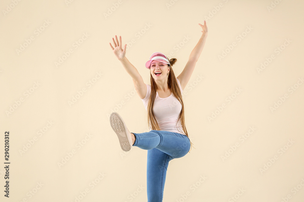 Cool young woman dancing against light background