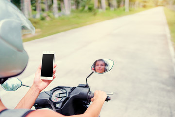 Wall Mural - Connection technology and transport. Young woman in helmet holding smartphone while driving motobike. Copy space on the screen.