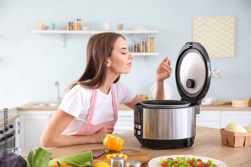 Woman using modern multi cooker in kitchen