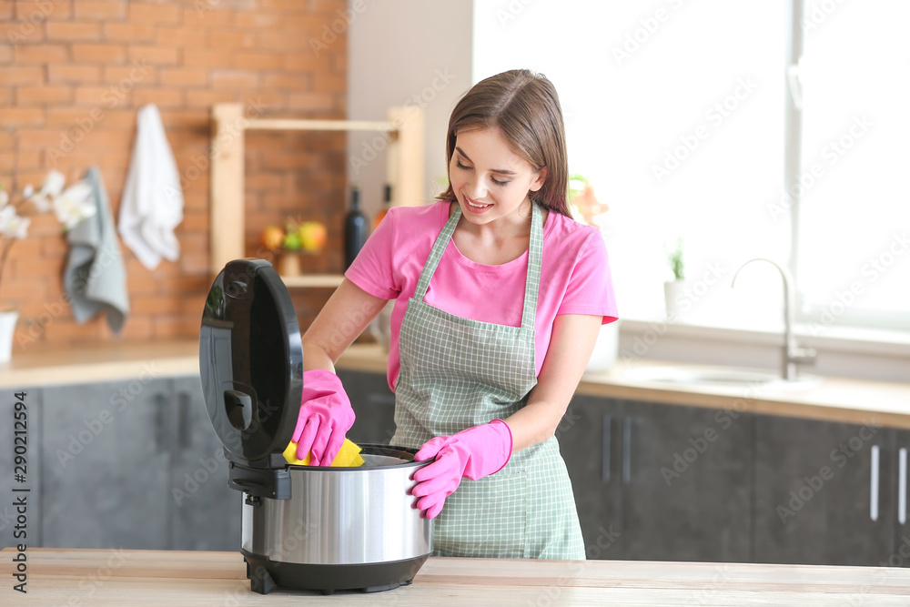 Woman cleaning modern multi cooker in kitchen