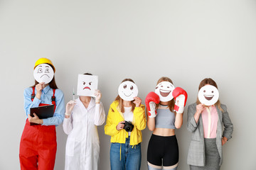 Sticker - Group of female workers covering their faces with drawn emoticons against light background