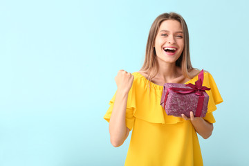 Poster - Happy woman with gift box on color background