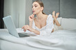© ZoomTeam - casual beautiful woman working on a laptop  on the bed in the house.