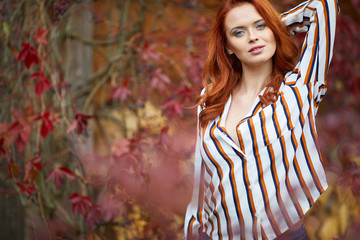 Wall Mural - Smiling redhead outdoors backlit by sun, fashion shoot. Close up woman portrait . redhair girl. Beautiful young woman close-up in autumn .