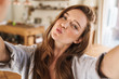 © Drobot Dean - Beautiful happy ginger woman indoors at home take selfie by camera.