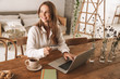© Drobot Dean - Business woman sit indoors in office using laptop computer holding credit card.