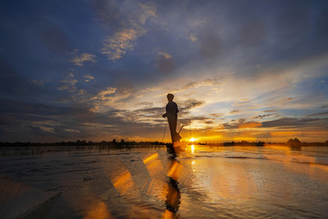 Wall Mural - Silhouette of Fisherman on fishing boat with net on the lake at sunset, Thailand