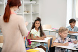 Fototapeta  - Girl wearing striped dress looking at teacher