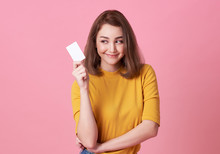 Portrait Of A Young Woman Showing Credit Card And Looking Isolated Over Pink Background