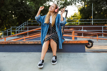 Wall Mural - Positive young teenage girl outside in park holding mobile phone.