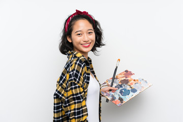 Young artist woman holding a palette over isolated white background smiling a lot