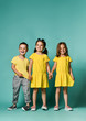 © FAB.1 - portrait of children on a light background: full body shot of three children in bright clothes, two girls and one boy. Triplets, brother and sisters.