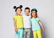 © FAB.1 - Studio portrait of children on a light background: full body shot of three children in bright clothes, two girls and one boy. Triplets, brother and sisters.