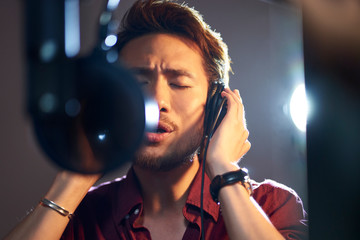 young asian singer singing in recording studio