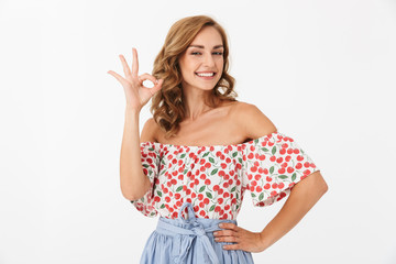 Happy smiling pleased woman posing isolated over white wall background make okay gesture.