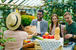 © silverkblack - Happy young people buying organic food in market talking to female farmer shop assistand standing in queue near stall in greenhouse. Youth and health concept.
