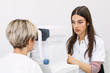 © Graphicroyalty - Pleasant woman with blue eyes having her eyes checked in binocular apparatus the oculist in eyes clinic doing cornea and retina exam diagnostic high technology concept eyes care