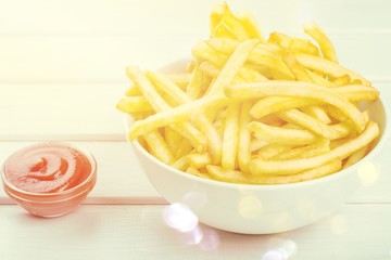 Wall Mural - Paper box with pile of appetizing french fries over white planks background