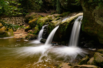 Wall Mural - idyllic small waterfall in lush green forest landscape