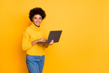 Copyspace photo of attractive intelligent cheerful business black stylish beautiful woman holding lap top with hands browsing through wearing yellow pullover isolated vivid color background