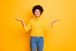 Photo of dark skin funny lady holding two new products on arms advising sale prices wear warm knitted pullover isolated yellow background