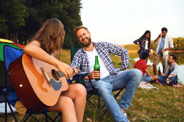 Wall Mural - Friends with a guitar on a picnic on nature in autumn.