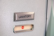Vacant red sign, occupied symbol on an airplane lavatory door. Raised, brushed metal lavatory sign, recessed plastic vacant sign. Toilet room, wc, closet on airplane board