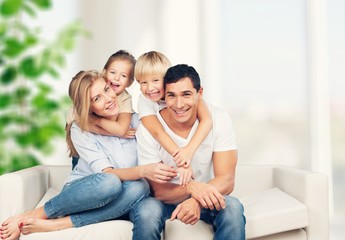 beautiful smiling family sitting at sofa at home