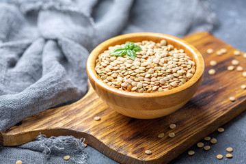 Wall Mural - Dry brown lentils in a wooden bowl.