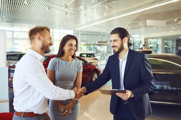 Canvas Print - A couple buys a new car. A man and a car salesman make a handshake