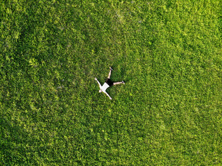 View from above happy man lying on fresh green grass relaxing