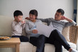 © Bo Bo/Stocksy - Happy asian family reading story in sofa at home