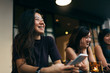 © Santi Nunez/Stocksy - Asian friends women using the mobile in the coffee shop.