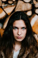 Portrait Of A Beautiful Brunette Woman With A Wooden Pile Behind