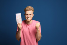 Portrait Of Happy Young Man With Lottery Ticket On Blue Background