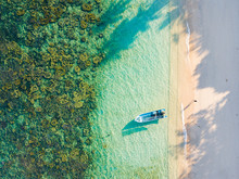 Aerial View Of A Woman Walking On A Sandy Beach And A Boat Aground In Kapas Island, Malaysia