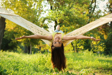 Wall Mural - Young woman resting in comfortable hammock at green garden