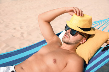 Wall Mural - Young man relaxing in hammock on beach