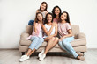 © New Africa - Happy women sitting on sofa near white wall. Girl power concept