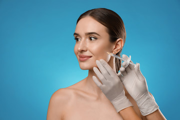 Poster - Beautiful woman getting facial injection on light blue background. Cosmetic surgery