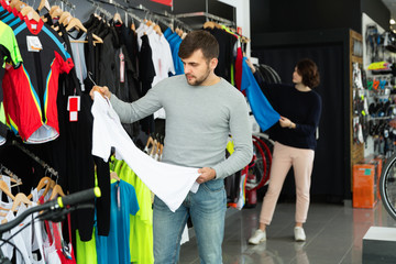 Couple choosing sport shirt in bicycle shop