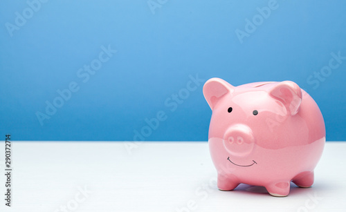 Fotografía Pink piggy bank on a blue background. Copy space for text.